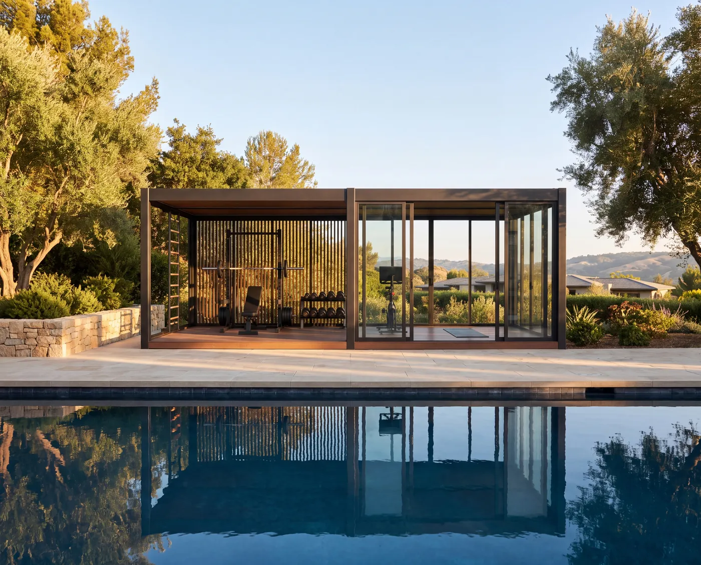 A glass-walled OS1 pavilion reflected in a pool at golden hour