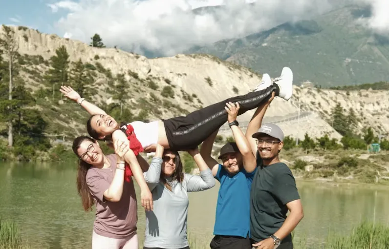 Teammates lifting a colleague into the air beside a lake